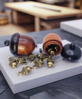 Hella Slick Screw Open Miniature Black Ebony Acorn Curios Set Of Two With Hidden Antique Bronze Pinecones on display.