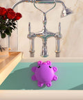 Hot Pink Silicone Bathtub Overflow Drain Cover For A Deeper Soak in use on bathtub, showing octopus suction cups.