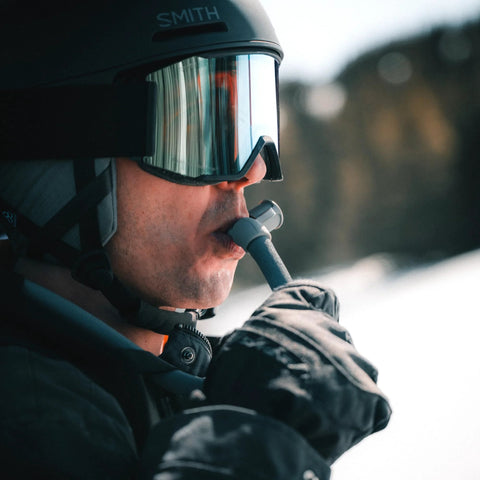 Close-up of HydraPak ArticFusion insulated drink tube mouthpiece, 1/4 inch, gray, used by skier with helmet and goggles.