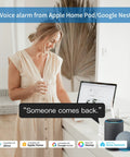Woman in a dress using a laptop with smart speaker on counter showing voice alarm feature from Apple HomePod and Google Nest.