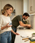 Woman holding Heavy Duty Concrete Crack Filler Fast Drying Waterproof Sealant in kitchen, man repairing sink.