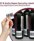 Hand holding 2x2 Inch White RF 8.2MHz Paper Security Labels With Fake Barcode Checkpoint Compatible Anti Theft EAS Loss Prevention