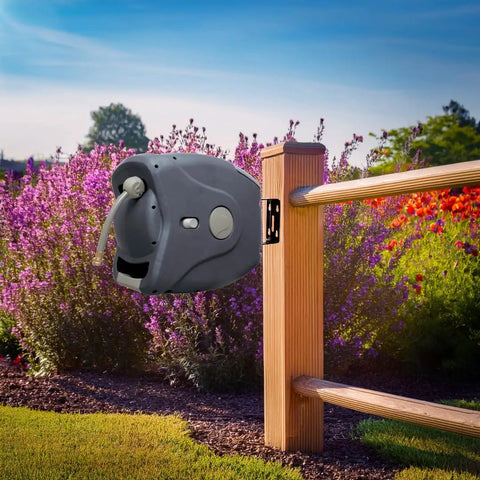 100 Ft Retractable Hose Reel with Wall Mount installed on fence in garden, showcasing auto rewind and charcoal finish