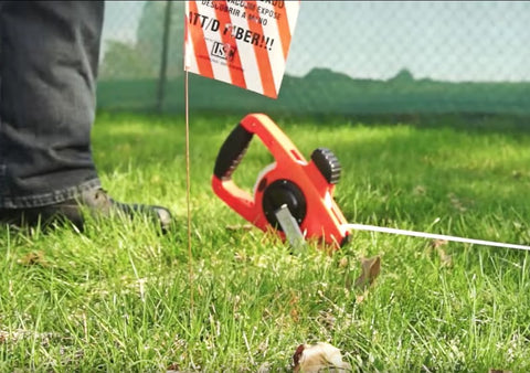 NRS18M330 Nylon Reinforced Tape Measure With Beast Speed Rewind and Dual Hooks used in grassy field for measurement.