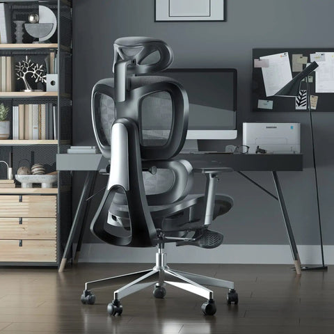 Black ergonomic office chair with footrest for long hours, adjustable lumbar support, and mesh back in home office setting.