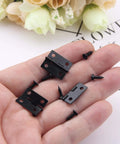 Hand holding 50 Pcs Mini Black Hinges For Wooden Boxes With 240 Replacement Screws 18 x 15mm Matte Iron Retro Handy Hardware Kit