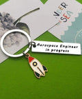 Funny Aerospace Engineer Keychain Gift For Graduation And Appreciation featuring rocket charm and tag on green background.