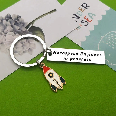 Funny Aerospace Engineer Keychain Gift For Graduation And Appreciation featuring rocket charm and tag on green background.