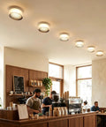 Modern Round LED Wall Sconce, 8W Smoke Grey Striped Glass Vanity Light illuminating a café interior from the ceiling.