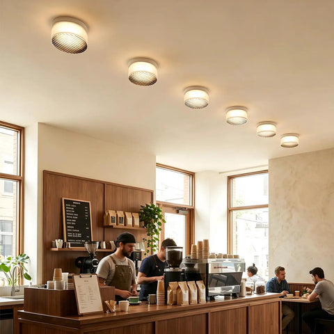 Modern Round LED Wall Sconce, 8W Smoke Grey Striped Glass Vanity Light illuminating a café interior from the ceiling.