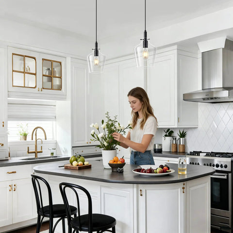Kveosv 2 Pack Kitchen Island Pendant Lights, 8" Clear Glass Shade Black fixtures illuminating a modern kitchen with woman arranging flowers.