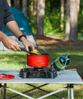 Man cooking with Portable 7500 BTU Propane Camping Stove With Precise Temperature Control For 12 Inch Pans in forest setting