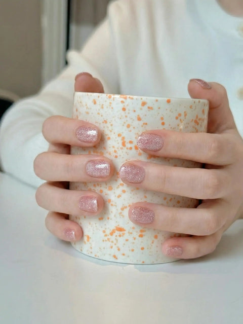 Hands holding a speckled mug showcasing pink cat eye glitter nails using Semi Cured Gel Nail Strips Kit With Cat Eye Glitter Pink Wraps