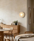 MECOLA Round Resin Accent Wall Sconce Small Glass Globe Shade Wall Lamp mounted on wall in a cozy dining area.