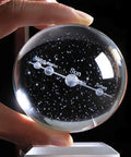 Stellar 80mm Solar System Crystal Ball Glass Sphere with 3D Laser Engraved Planets, K9 Crystal, held by hand, close-up view.