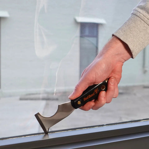 Person using Six In One Painter Tool for DIYers with scraper on window frame, featuring solvent resistant nylon handle and high carbon steel blade.