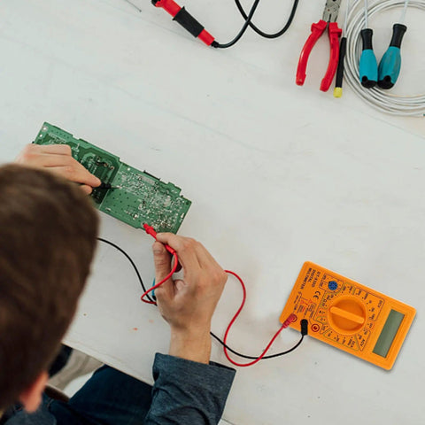 Person using 830D Digital Multimeter Tester With Buzzer 1999 Counts for electronics work on a circuit board on a table.
