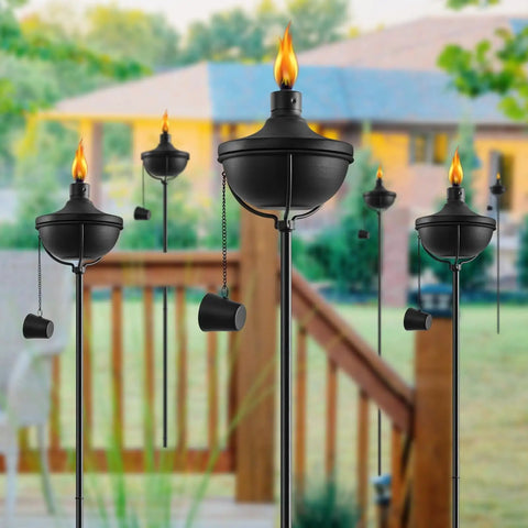 Six Pack 24 Oz Outdoor Garden Torch Set With 55 Inch Citronella Metal Torches And 3 Prong Grounded Stakes in a yard.
