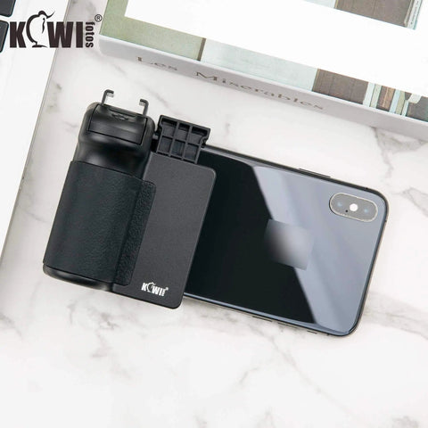 Compact Phone Camera Grip Handle With Tripod Mount Remote Shutter And Cold Shoe Adapter attached to smartphone on marble surface