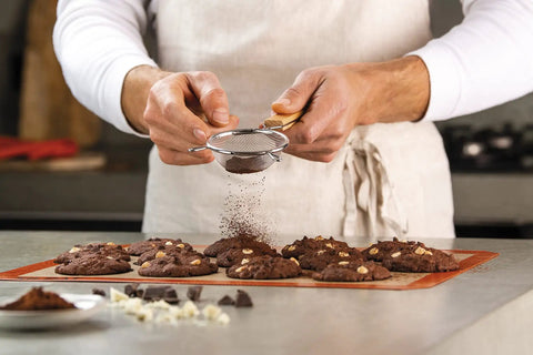 Chef using Nonstick Silicone Baking Mat For Cookies, Pro Grade Quality With Fiberglass Mesh For Even Heat, Reusable Oven Microwave And Freezer Safe, Easy Cleanup, Cookie Size, Bakes Like A Boss For Home Bakers And Pro Chefs to bake cookies.
