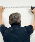 Man using Kickass Cordless Drill Driver Pack Featuring Knockout Torque And Boss Level Brushless Motor to install metal track on wall.