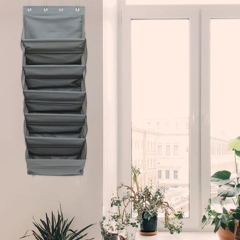Straight Up Game Changer Over The Door Shoe Rack With Six Roomy Pockets against a wall next to a window with plants.