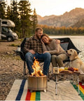 Couple sitting on Oversized Heavy Duty Camping Loveseat With Cup Holders by lake with dog and fire pit