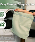 Person placing a grass green wet bag in a washing machine, highlighting the Waterproof Wet Bag Set For Baby On The Go.