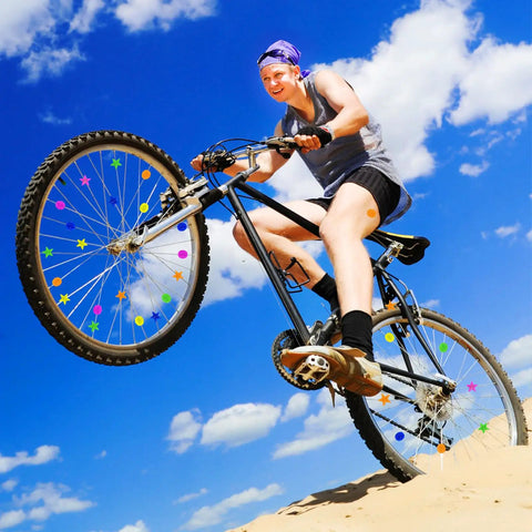 Cyclist jumping with bike showing colorful 72 Piece Bike Spoke Beads Set with assorted shapes and colors for wheel decorations.