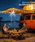 Portable Tent Fan With Built In Lights And Remote USB Rechargeable Camping Fan Wireless Tent Fan With 4 Speeds And Timer Battery Powered Ceiling Fan For RVs Trucks Rooftop Tents And Travel Camping in use, illuminating a campsite next to a Jeep with people relaxing underneath.