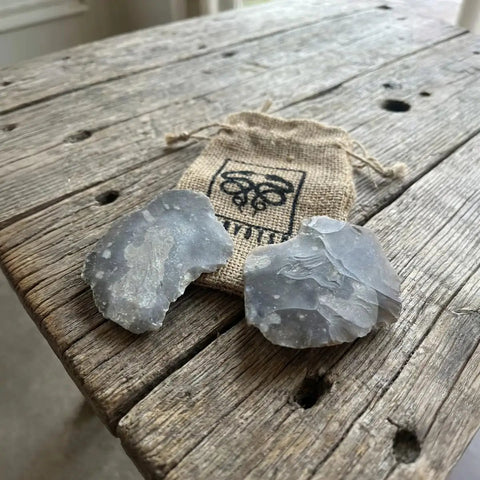 English Flint Fire Starter Kit with two UK flint stones on rustic wood table and emergency jute tinder bag for bushcraft camping and survival.
