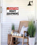 Caution Heavy Equipment Warning Metal Sign 8x12 Inch Aluminum Wall Decor on porch with chair and plants visible