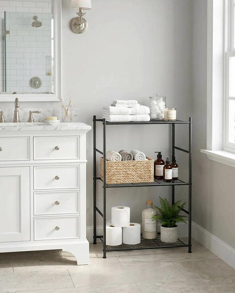 Three Tier Metal Storage Shelf Organizer For Small Spaces With Adjustable Feet Space Saving Heavy Duty Shelving Unit For Kitchen Garage And Laundry Room Each Shelf Supports Up To 100 Lbs Black, shown next to a bathroom sink, holding towels and toiletries.