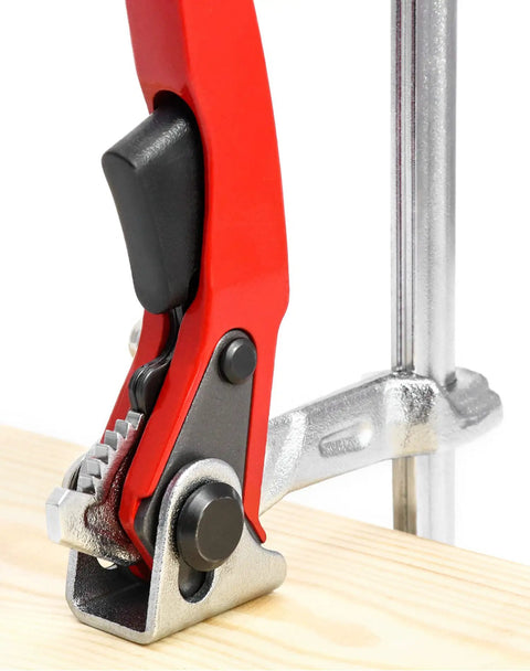 Close-up of ratcheting table clamp set quick release bar clamps for sanding and cutting with metal grip on wooden surface.