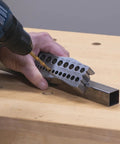 Person using all metal handheld drill guide for straight holes with twenty five drill guides in one one eighth to one half inch