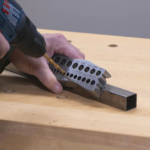 Person using all metal handheld drill guide for straight holes with twenty five drill guides in one one eighth to one half inch
