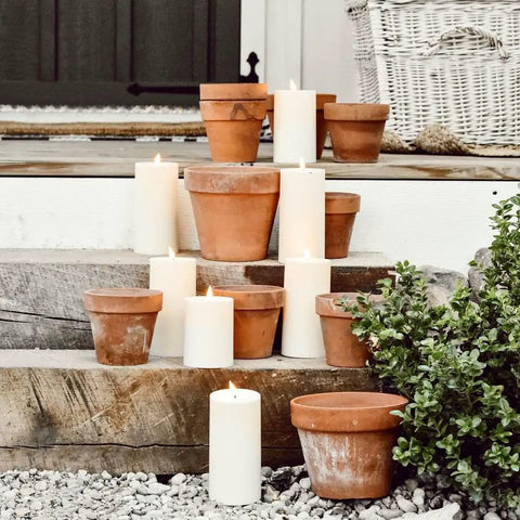 Waterproof Outdoor Flameless Pillar Candles 3 Pack In Ivory Resin, 3x4, 3x5, and 3x6 inches on rustic steps with terracotta pots