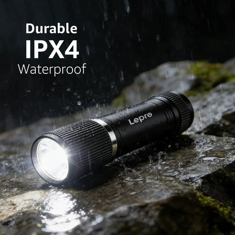 Compact LED Mini Flashlight with Tiny but Mighty Brightness, waterproof IPX4, shining in rain on rocky surface.