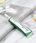 Flux Paste For Soldering, 15ml tube, placed on a marble surface next to a grey cloth and lemon slices, improves conductivity.