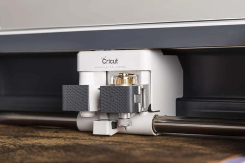 Cricut knife blade and drive housing installed under the Cricut Maker; white unit with gray A and B tool blocks.
