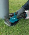 18V LXT Cordless Grass Shear With Hedge Trimmer Blade being used to trim grass by a pole