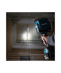 Man holding 18V LXT Cordless LED Flashlight Spotlight With Four Modes 600 Lumens Spot 1000 Lumens Flood in a dimly lit stairwell.