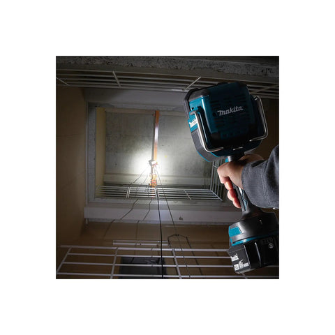 Man holding 18V LXT Cordless LED Flashlight Spotlight With Four Modes 600 Lumens Spot 1000 Lumens Flood in a dimly lit stairwell.