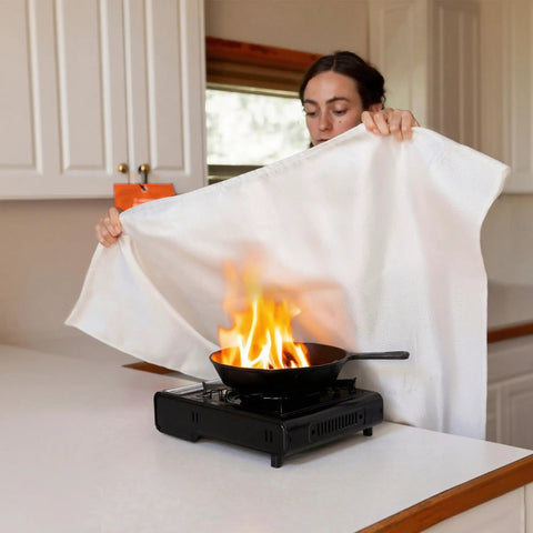 Person using Two Pack Fire Blanket 40 By 40 Inches for Kitchen And Home Emergency Fire Suppression on stovetop flame.