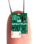 Ultra Tiny SRXL2 DSMX Serial Micro Receiver for RC Gearheads, Model SPM4650, displayed on fingertip, showcasing compact size