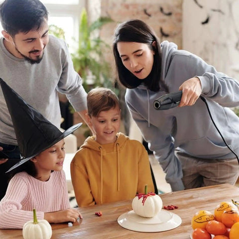 Person using Mini Heat Gun With Reflector Nozzles Kit 350W Fast Heat Hot Air Gun for crafting on table with children watching.