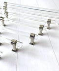 Set of clear chrome finish Lucite acrylic cabinet pulls in various sizes on white background