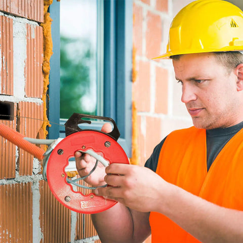 Wxtools 100 Ft Fish Tape For Electric Wire Pulling Reel With Durable Handle and Thumb Lock used by a worker in a construction setting.