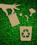 Cardboard cutouts of a hand holding biodegradable mailers and recyclable bin on grass backdrop