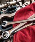 Open End Ratcheting Wrench Set, 8-Piece SAE 12-Point placed on red cloth near engine parts